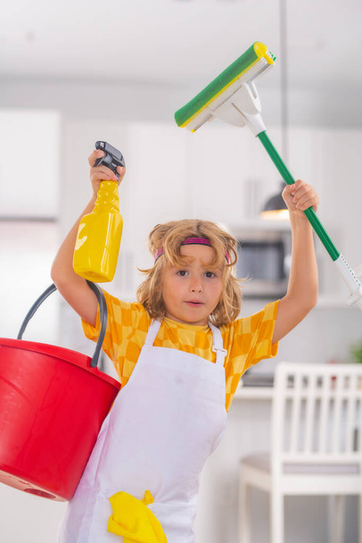 Portrait of child cleaning, concept growth, development, family relationships. Housekeeping and home cleaning concept. Child use duster and gloves for cleaning. Home kitchen background - Photo, Image