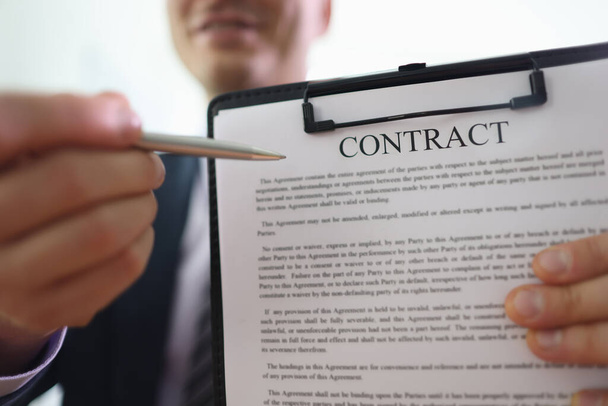 Businessman holds clipboard in hand pointing pen to contract papers. Man demonstrates rules written in agreement document before signing - Foto, Bild