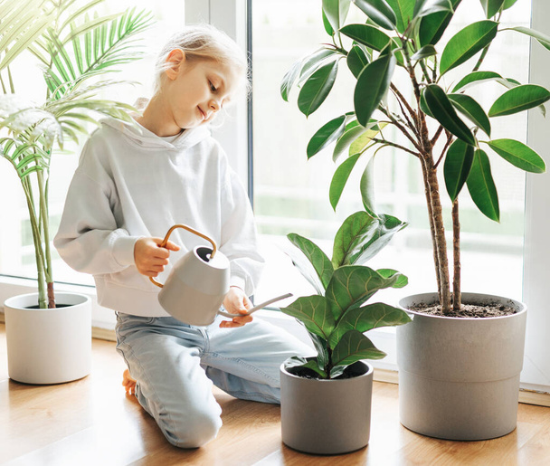 Little girl watering and caring for house plants - Foto, imagen