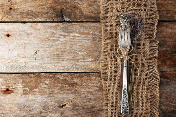 Silverware tied with rope burlap cloth and rustic wooden planks background - Photo, image