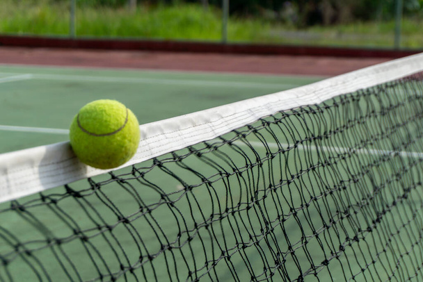 テニスボールを閉じてネットの上をクリップします。テニスボールがネットを打って反対側に行きます。テニスコート - 写真・画像