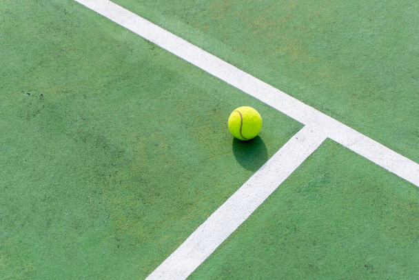 Top angle view of tennis ball on court. Yellow tennis ball on green court and white lines. - Photo, Image