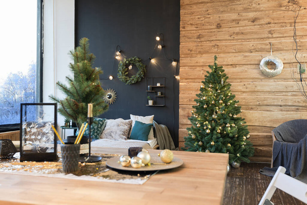 On the eve of the holiday, the interior of the country house is decorated with a New Year tree. large spacious light room decorated with wood with simple wood furniture - Fotografie, Obrázek