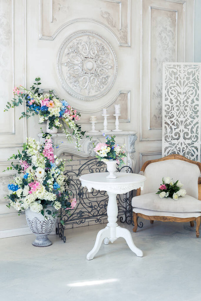 花瓶の花と明るい高級白と青のインテリアリビングルーム。壁にはバロック様式の装飾が施されています - 写真・画像