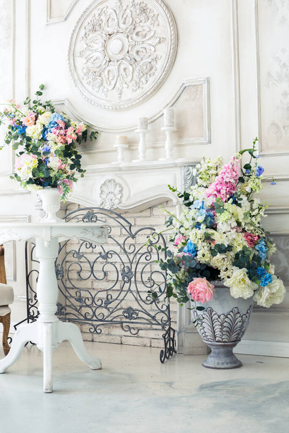 花瓶の花と明るい高級白と青のインテリアリビングルーム。壁にはバロック様式の装飾が施されています - 写真・画像