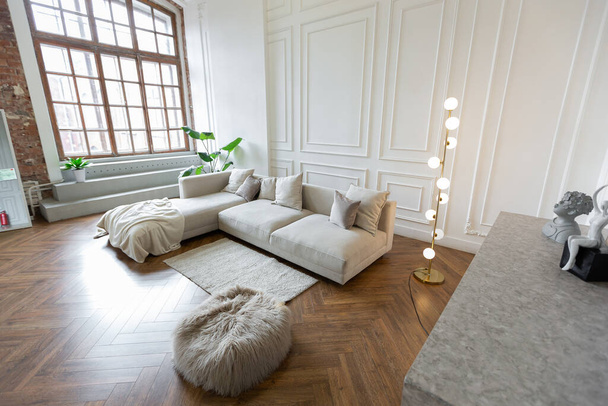 interni minimalisti di un appartamento ultra moderno open space con pareti bianche e grigie con un rilievo e grigio mobili imbottiti alla moda e grandi finestre - Foto, immagini