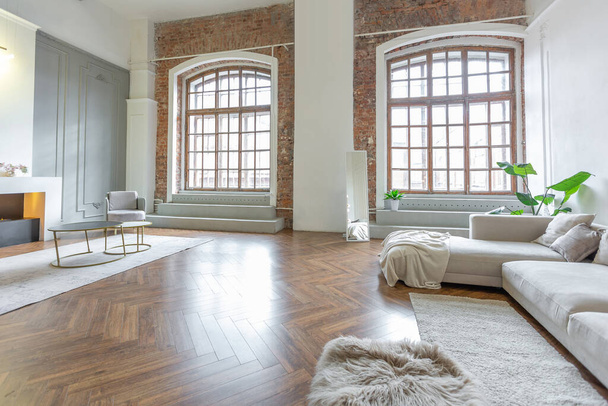 Minimalistisches Interieur einer hochmodernen, offenen Wohnung mit weißen und grauen Wänden mit Relief und grauen, stilvollen Polstermöbeln und riesigen Fenstern - Foto, Bild
