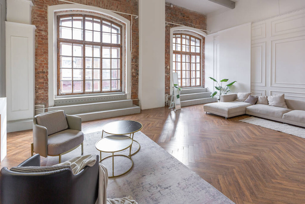 minimalistyczne wnętrze ultra nowoczesnego mieszkania na otwartym planie z białymi i szarymi ścianami z płaskorzeźbą i szarymi stylowymi meblami tapicerowanymi i ogromnymi oknami - Zdjęcie, obraz