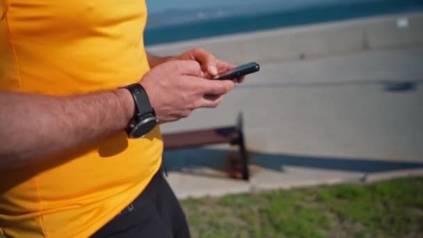 Zamknij Jogging człowiek za pomocą smartfona po uruchomieniu aktywności sportowej. Aplikacja mafii, nadajnik, szybkość, bicie serca. Biegacz dorosły po treningu za pomocą aplikacji sportowych na telefon komórkowy - Materiał filmowy, wideo