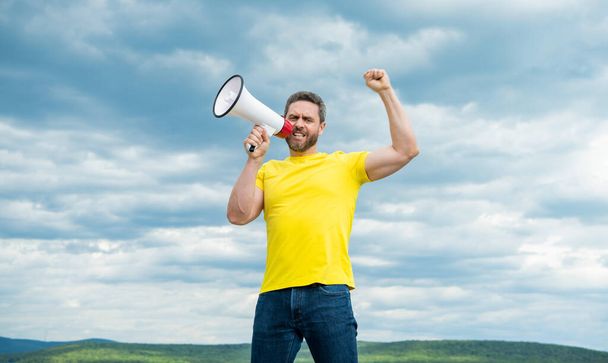 man announcer in yellow shirt shout in megaphone on sky background. - Fotó, kép