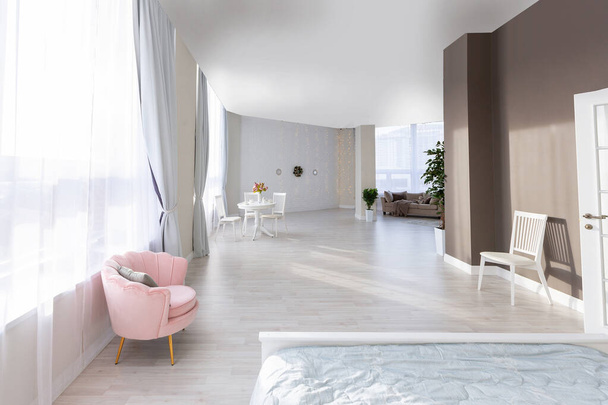 Luxurious and expensive interior of an open-plan apartment in light colors. Stylish modern bedroom with minimal design, dining area and guest space. - Foto, imagen