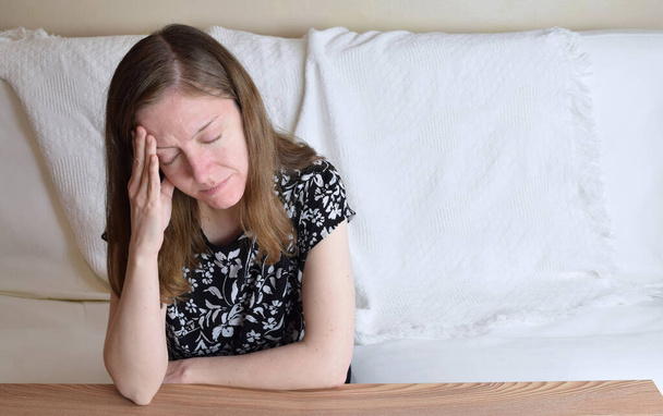 Closeup of an anxious woman resting her head on her hand surrounded by plenty of white copy space. - Photo, Image