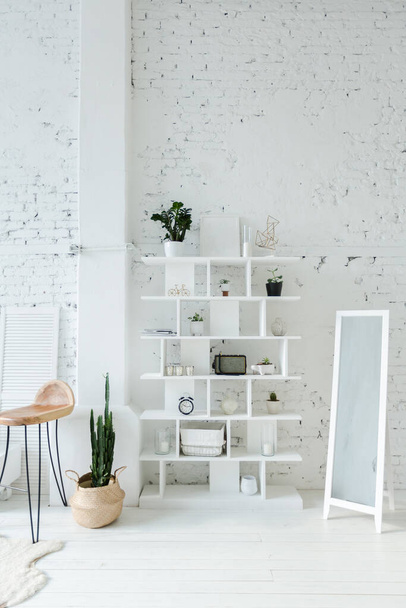 Spacious stylish modern trendy loft apartment in white and light colors. a large room full of sunlight. brick wall, wood floor, shelving, pallet bed and huge window. everything is white with gray tints. - Φωτογραφία, εικόνα