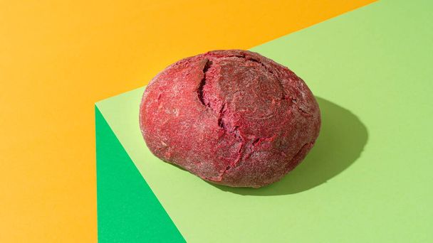 Beetroot bun on light green background. Healthy bread concept - Photo, Image