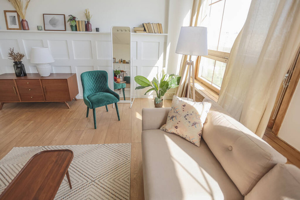 Vintage studio apartment interior in light colors in old style. huge room with large windows with a living room area and a bedroom area. direct sunlight inside. - Фото, изображение