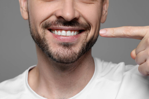Man showing healthy gums on gray background, closeup - Foto, imagen
