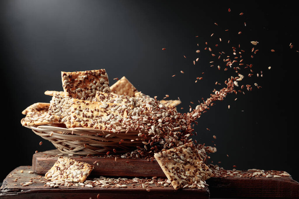 Sunflower seeds and flax seeds are poured on crispy crackers with sunflower seeds and flax seeds. - Photo, Image
