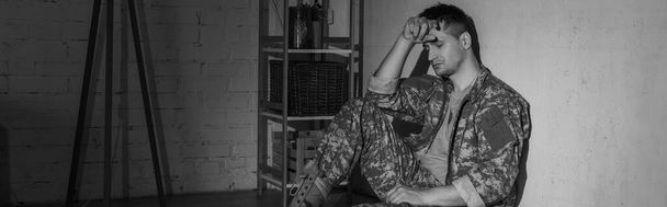Černobílá fotografie depresivního vojenského veterána sedícího doma, prapor  - Fotografie, Obrázek