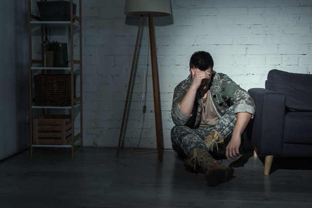 Soldaat in militair uniform die 's nachts thuis aan depressie lijdt  - Foto, afbeelding