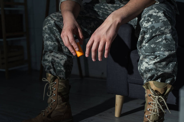 Vista recortada del soldado en uniforme con ptsd sosteniendo antidepresivos en casa  - Foto, Imagen
