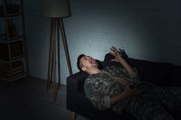 Geïrriteerde militair met posttraumatische stressstoornis schreeuwend thuis 's nachts  - Foto, afbeelding