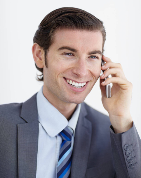 Networking is his speciality. A smiling young businessman talking on his smartphone - Foto, Bild