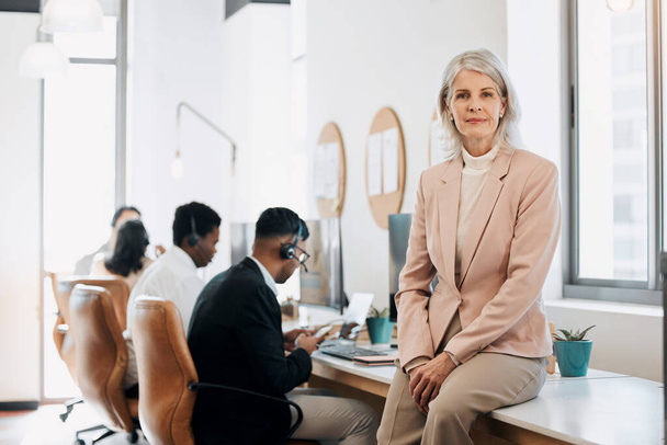 Здесь нет никакого микроменеджмента. зрелая деловая женщина, сидящая в офисе, пока ее команда работает за ее спиной - Фото, изображение