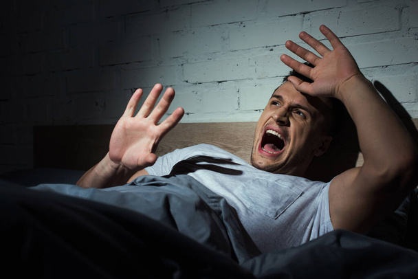 scared young man with ptsd having nightmares and screaming at night  - Photo, Image