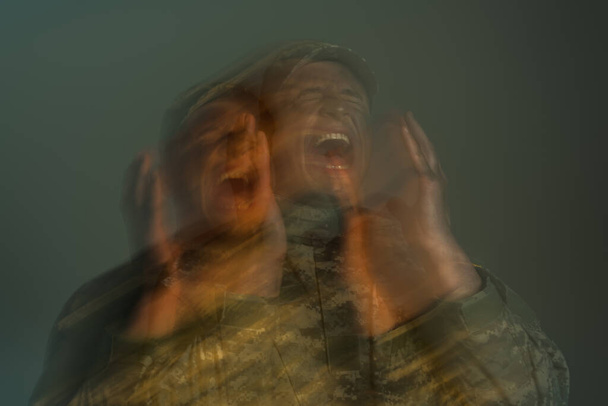 dlouhá expozice vojáka trpícího posttraumatickou stresovou poruchou a křikem izolovaným na šedi  - Fotografie, Obrázek