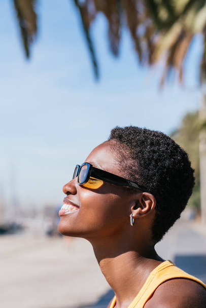 retrato vertical de um lado de uma mulher africana com cabelo muito curto olhando para longe - Foto, Imagem