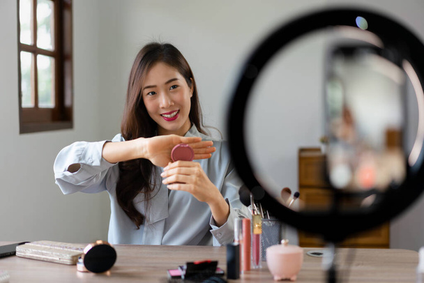 美容ブロガーは、上の赤面を保持し、メイクvloggerで化粧品をレビューする製品を示す. - 写真・画像