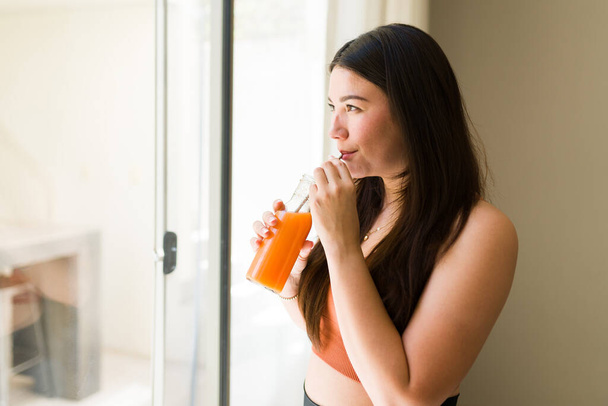 Relajada mujer fitness beber un jugo de zanahoria saludable y relajarse después de ejercicios de entrenamiento - Foto, imagen