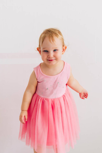 concept of children's emotions. Portrait of lovely toddler little baby child with pink dress - 写真・画像