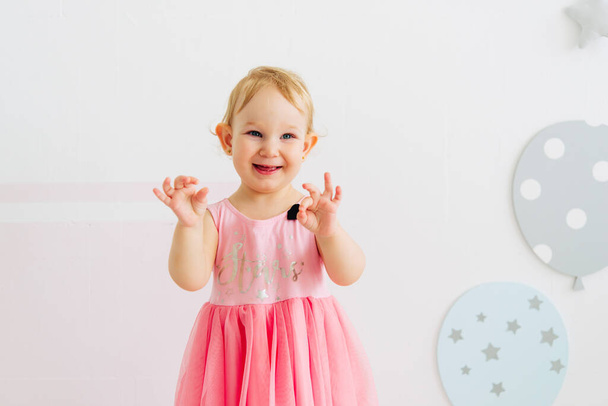 concept of children's emotions. Portrait of lovely toddler little baby child with pink dress - Foto, imagen