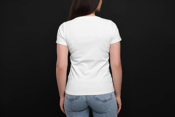 Woman wearing white t-shirt on black background, back view - Foto, immagini