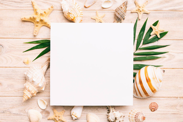 Summer time concept with blank greeting card and blank white paper on colored background. Seashells from ocean shore in the shape of frame separated with space for text top view. - Fotoğraf, Görsel