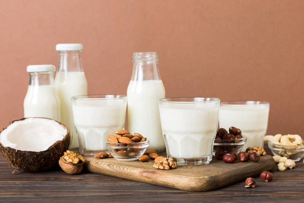 Set or collection of various vegan milk almond, coconut, cashew, on table background. Vegan plant based milk and ingredients, top view. - Photo, Image