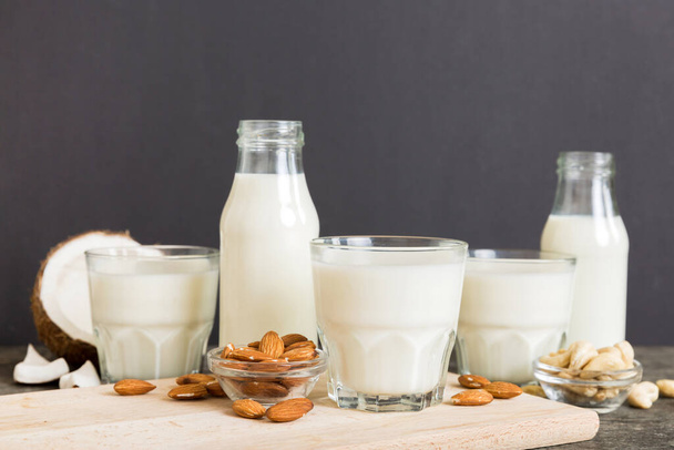 Set or collection of various vegan milk almond, coconut, cashew, on table background. Vegan plant based milk and ingredients, top view. - Photo, Image