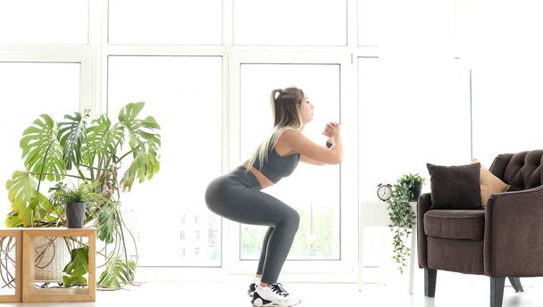Strong Athletic Fitness Girl in Sportswear Doing Exercises in Bright Living Room.    - Foto, immagini