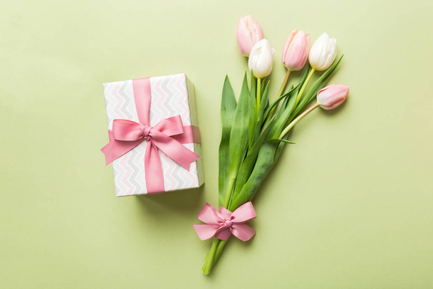 Pink tulips flowers and gift or present box on colored table background. Mothers Day, Birthday, Womens Day, celebration concept. Space for text top view. - Photo, image