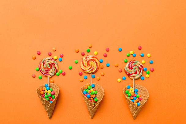 waffle cone full of assorted traditional candies falling out on colored background with copy space. Happy Holidays sale concept. - Fotografie, Obrázek