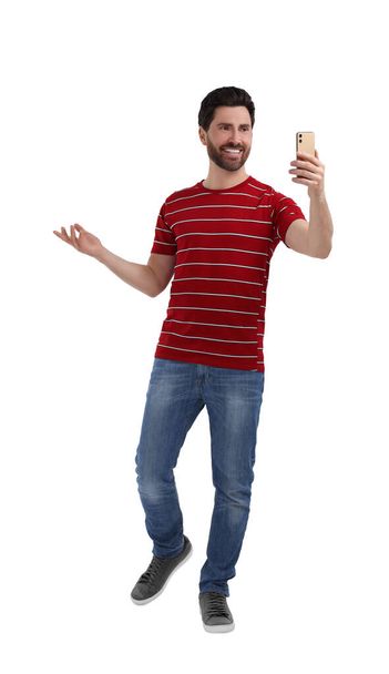 Smiling man taking selfie with smartphone on white background - Photo, Image