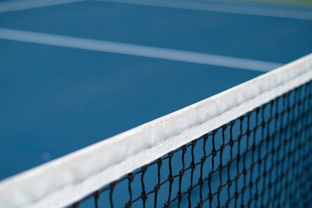 A closeup of a tennis net on the court on a sunny day with a blurry background - Foto, immagini