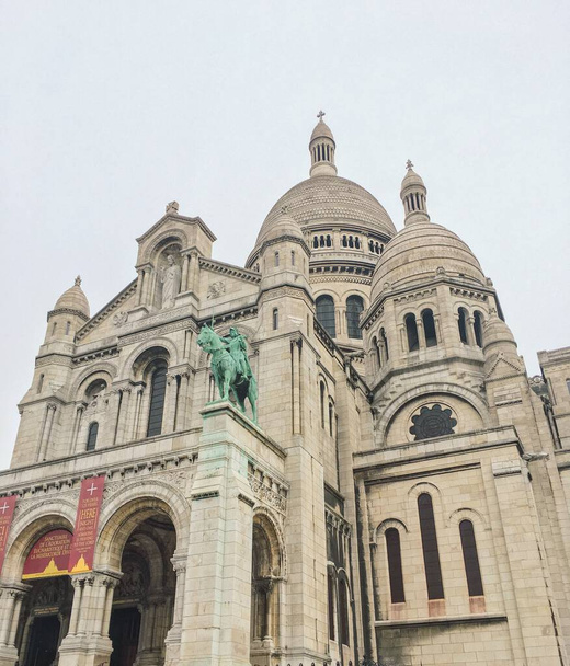 Un ángulo bajo de La Basílica del Sagrado Corazón de París con un cielo gris en el fondo - Foto, Imagen