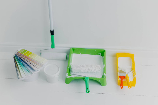 Photo of two trays with paint rollers, bucket with color and colour samples, white background. House renovation concept. Refurbishment - Fotografie, Obrázek