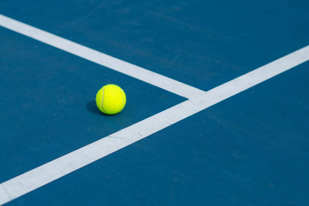 A landscape of a blue and green tennis court with a ball on it on a sunny day - Foto, imagen