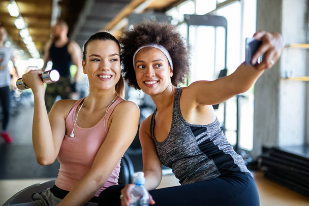 Beautiful young women working out in gym together to stay healthy. Sport, people, friend concept. - Foto, Bild