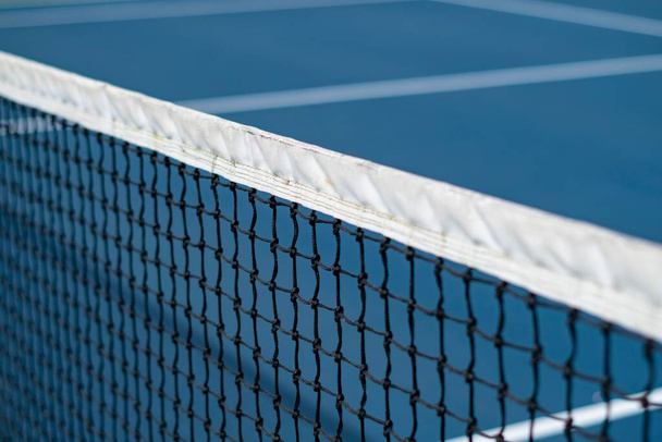 A close-up of the diagonal tennis net with white lines on a blue court, concept of a tennis match - Photo, Image
