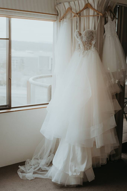 A hanging wedding dress in room - Foto, Imagen