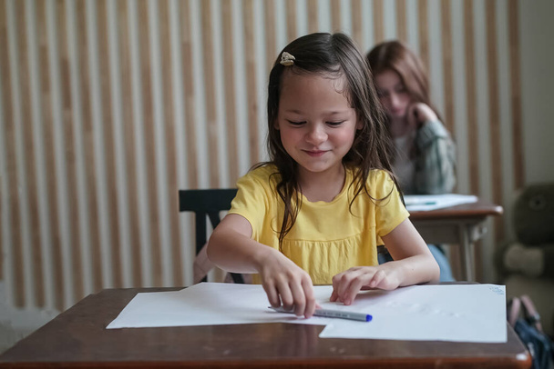 мила школярка сидить за столом у школі
  - Фото, зображення